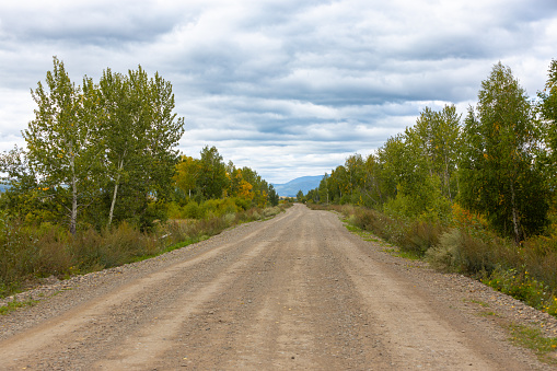 Landscape of empty rural gravel road in cloudy day. Dirt not asphalted road