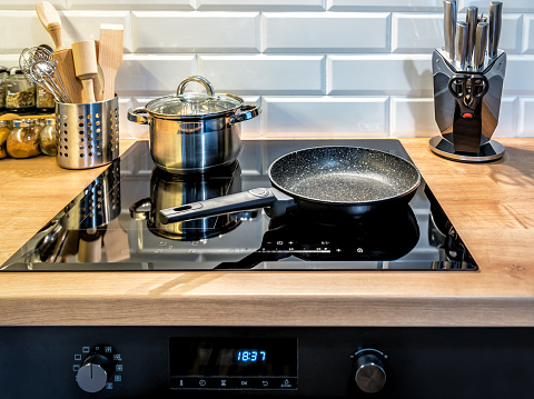 Stainless steel cooking pot and pan on induction hob in modern kitchen.