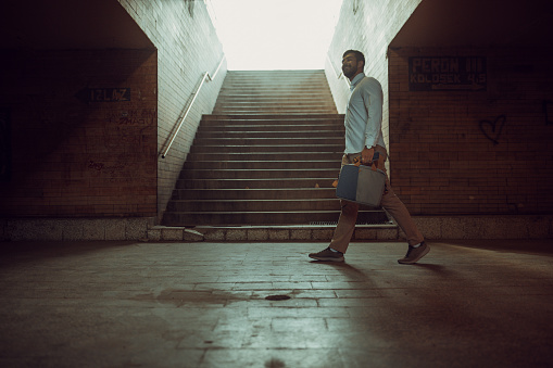 One man, modern young businessman with laptop bag walking alone in underpass.