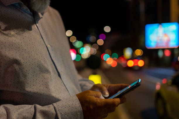 istock Male hands using smartphone in city at night time 1432295382