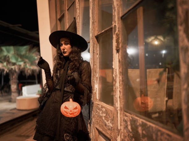 istock woman dressed as a witch smoking outdoors at night looking at the camera portrait 1432296383