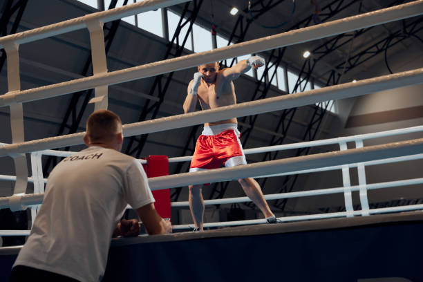 istock Two sportive men, professional boxer and personal trainer is practicing boxing at gym. Sport, strength, energy and power 1432298521