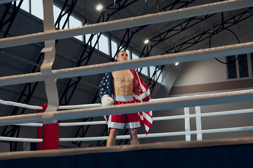 Winner emotions. Male boxer with american flag on his shoulders celebrating his victory. Strength, sport, facial expression and motion concept.