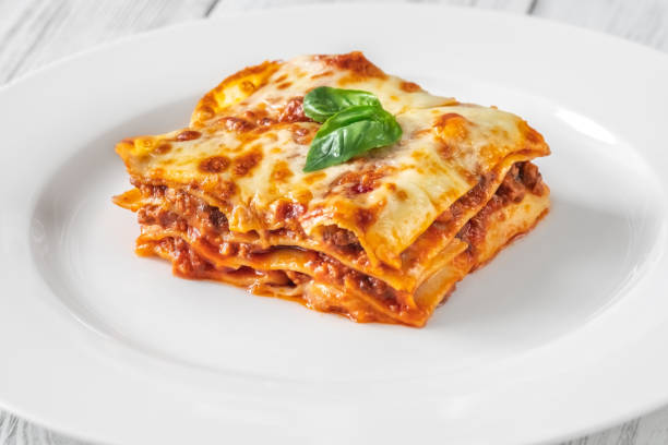 Portion of lasagne on white plate stock photo