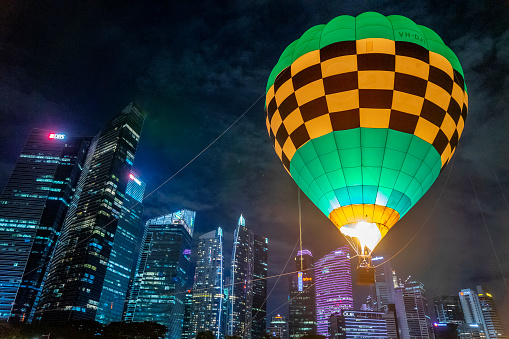 Singapore, Singapore - October 9, 2022: A tethered hot air balloon operated by Ballons du Monde floats in front of skyscrapers at Marina Bay.