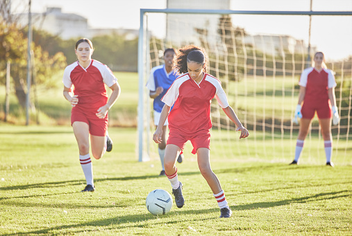 Female football, sports and team playing match on a field while kicking, tackling and running with a ball. Energy, fast and skilled sporty players in a competitive game against opponents outdoors