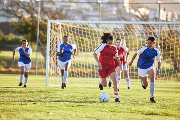 squadra sportiva, calcio femminile e kick ball sul campo in un torneo. calcio, competizione e atletica gruppo femminile di adolescenti giocano sull'erba. gli adolescenti in forma competono per vincere la partita al campionato scolastico. - termine sportivo foto e immagini stock