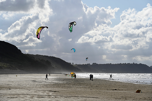 Erquy, September 24, 2022 - Tourists and locals on the beach of Caroual flying kites, kiteboarding and kite surfing, Brittany