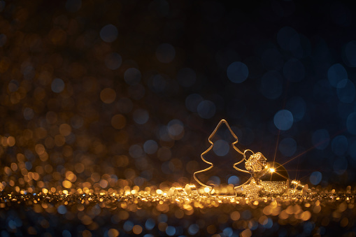 Decorative Christmas still life macro photography. Christmas tree cookie cutter and ornaments on gold and blue defocused lights. Native image size: 7952x5304