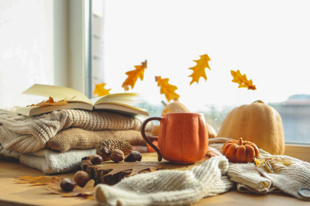 Autumn still life on the windowsill, a cup of tea, candles, pumpkins, leaves, thanksgiving house interior stock photo