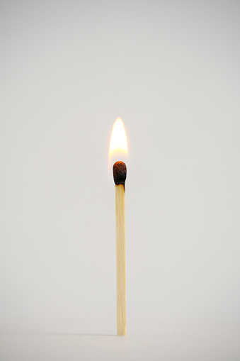 Standing, burning match on a light background
