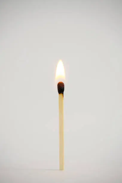 Photo of Standing, burning match on a light background.