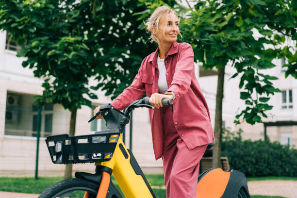 uma jovem usa uma bicicleta elétrica alugada urbana. energia verde. - bikeshare - fotografias e filmes do acervo