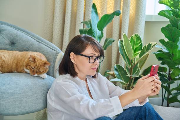 istock Mature woman sitting at home, using smartphone 1432312902
