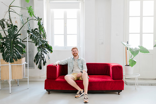 Smiling mid adult man sitting on sofa at living room