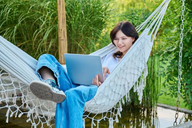 istock Teenage girl relaxing in hammock using laptop for leisure study 1432313859