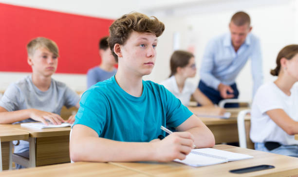 istock Young students sitting at desks in classroom 1432318965
