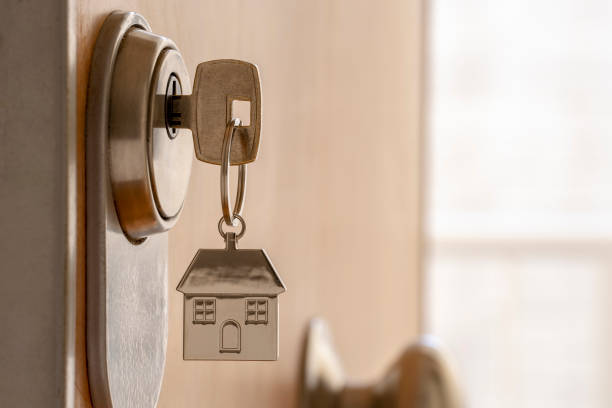 CLOSE UP OF KEY AND HOUSE KEYCHAIN ​​IN HIGH SECURITY DOOR LOCK. HOME INSURANCE CONCEPT. COPY SPACE. CLOSE UP OF KEY AND HOUSE KEYCHAIN ​​IN HIGH SECURITY DOOR LOCK. HOME INSURANCE CONCEPT. COPY SPACE. villa stock pictures, royalty-free photos & images