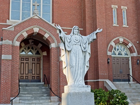 The front of Sacred Hearts Catholic church in Bradford - Haverhill Massachusetts, September 2022. The entry and statue of Jesus on this large brick church.