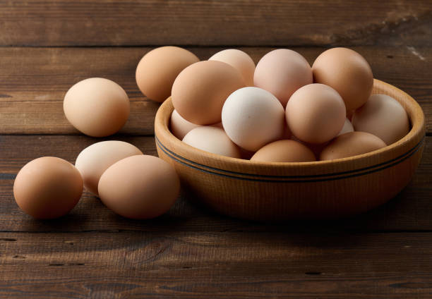 istock Fresh brown chicken eggs in a round wooden plate on the table 1432331223