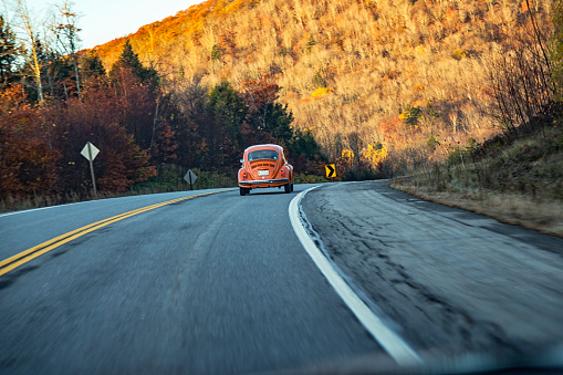 Vintage early 1970's Volkswagen Beetle bug car speeding along Maine State Route 46 near the town of Eddington, Maine, USA, on the morning of October 23, 2013.