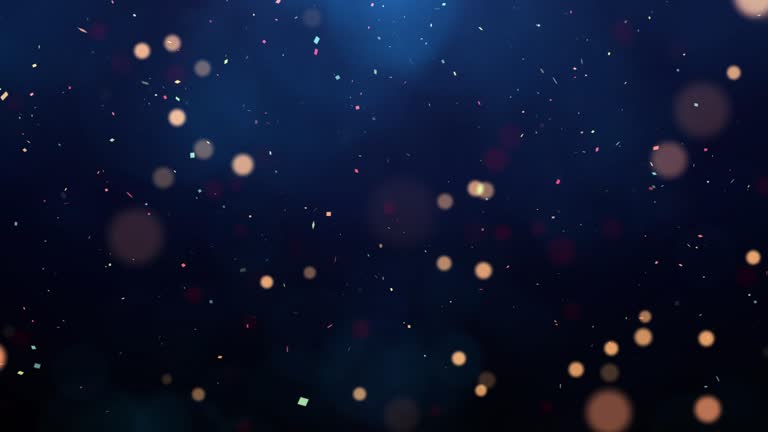 abstract background of the new year festival celebration slow moving particles and confetti on dark blue background.