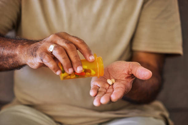 Medicine, healthcare and pills in the hands of a senior man sitting on a sofa in the retirement home. Prescription, medication and antibiotics for chronic treatment and wellness with a pensioner Medicine, healthcare and pills in the hands of a senior man sitting on a sofa in the retirement home. Prescription, medication and antibiotics for chronic treatment and wellness with a pensioner prescription medicine stock pictures, royalty-free photos & images