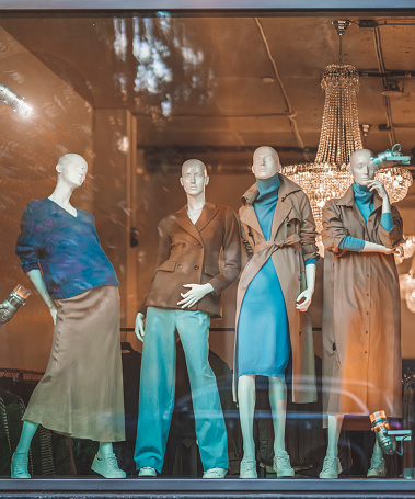Female mannequins in shop window with demi-season clothing, street reflection. Shopping concept