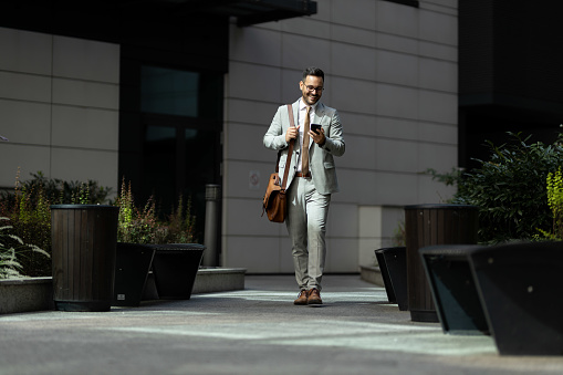 Business man in front of modern office building
Business man walking of his office and looking on phone