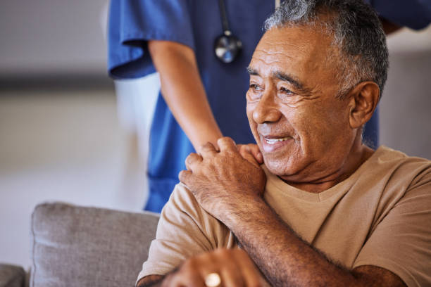 Nurse or doctor give man support during recovery or loss. Caregiver holding hand of her sad senior patient and showing kindness while doing a checkup at a retirement, old age home or hospital stock photo