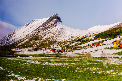 Green field. Picturesque sunny landscape in Norway. Snow on mountain. Spring. Beautiful north nature. Scandinavia. Adventure in mountains. Norwegian climate