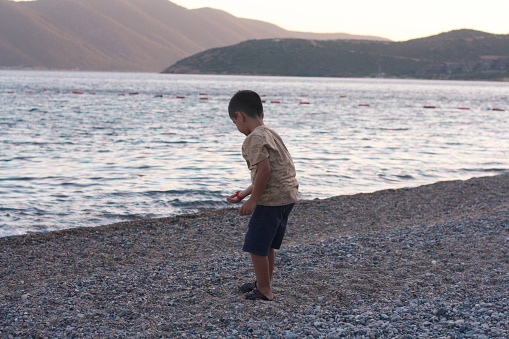 A young boy throws a stone as hard as he can into the sea on his summer holiday.