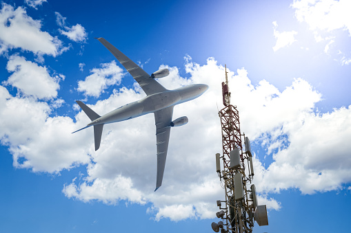 Mobile phone cell tower with 5G on the C Band frequencies with aircraft on the background. Airlines worried about interference with plane altimeter