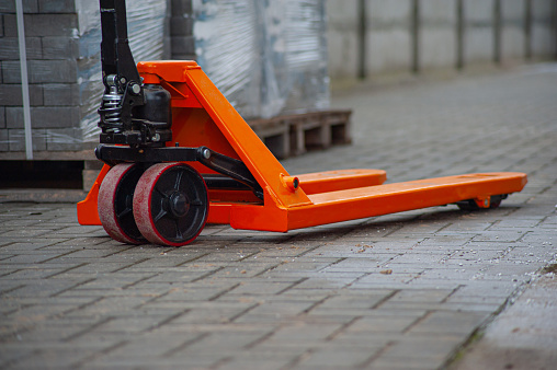 Old orange manual hand pallet trucks. Close up wheel of hydraulic hand pallet truck.