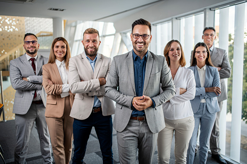 Multiracial group of happy business colleagues standing in a hallway of an office building and looking at camera.