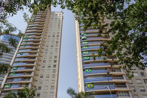 Goiânia, Goias, Brazil – September 28, 2022: Two residential buildings with several Brazilian flags on the windows.