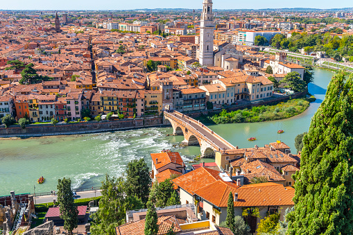 View of the historic center of the city of Verona, Italy and the Ponte Pietra bridge and river Adige from the hillside fortress of Castel San Pietro, with groups of rafters enjoying a ride on the river.