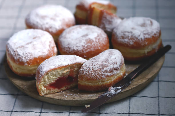 Berliner donuts in powdered sugar on a wooden tray. stock photo