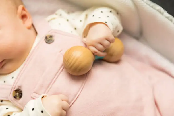Baby holding a wooden rattle toy
