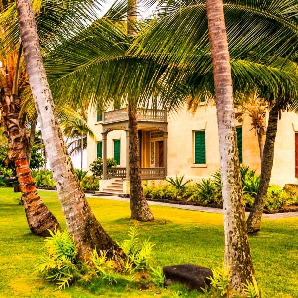 Kona, United States - September 06, 2012 : A tropical mansion / house with a garden with palm trees, tropical plants and a lawn