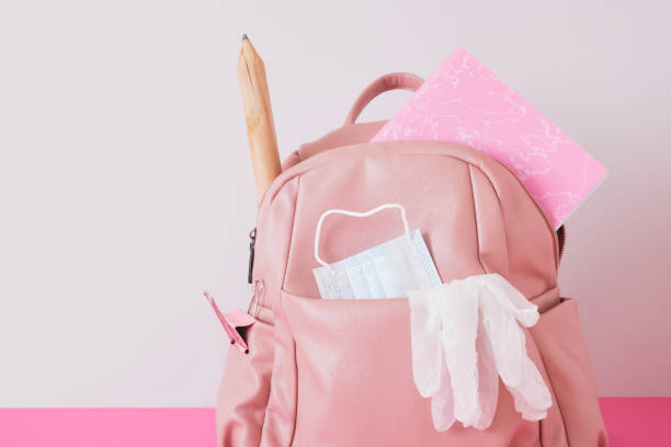 istock leather pink backpack on the shoulders on a gray background,, face mask and gloves, lockdown at school 1432383128
