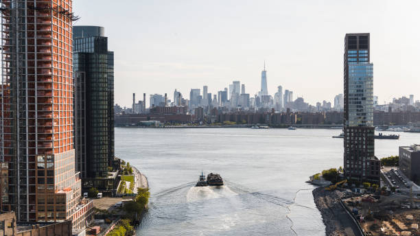 bajo manhattan con vista panorámica lejana de la torre de la libertad desde el río newtown creek en greenpoint, brooklyn. el remolcador está tirando de una barcaza con chatarra a lo largo del río. - green point fotografías e imágenes de stock