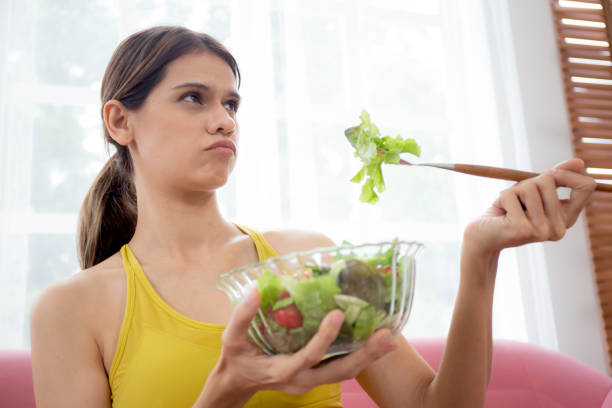 istock Young caucasian woman sitting on sofa eating vegetable salad while feeling dislike and expression disgusted, woman emotion frustrated with anorexia vegetarian and hate, nutrition food concept. 1432385437