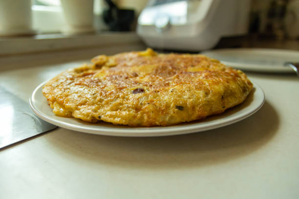 Slices of spanish omelette, a beloved traditional dish featuring eggs, potatoes, and onions, are beautifully arranged on a white plate, inviting enjoyment and satisfaction
