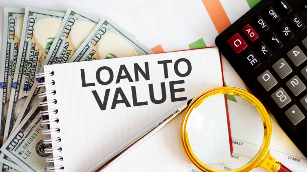 LOAN TO VALUE is written on notebook on a chart background with dollars and calculator stock photo
