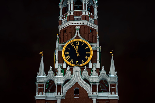 12 hours on the chimes of the Spasskaya Tower of the Moscow Kremlin against the background of a dark cloudy sky. 5 minutes until the new year.