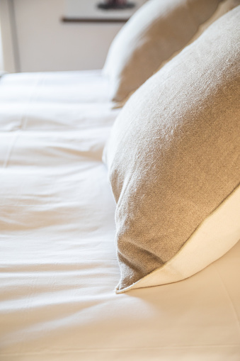 Detail of two natural linen cushions on a homemade bed
