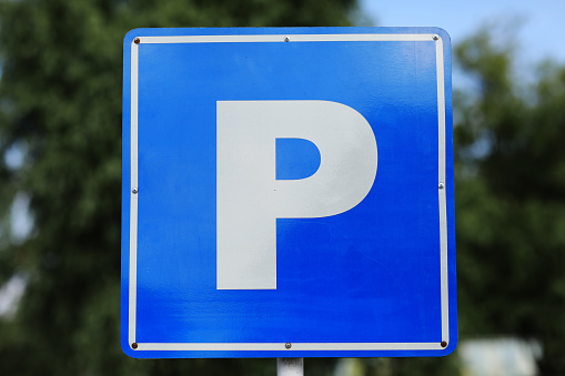 Closeup of a modern free parking sign road sign on nature park background. Isolated parking blue road sign with letter P on rectangular plate.