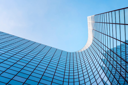 low angle view of a contemporary glass skyscraper reflecting the blue sky