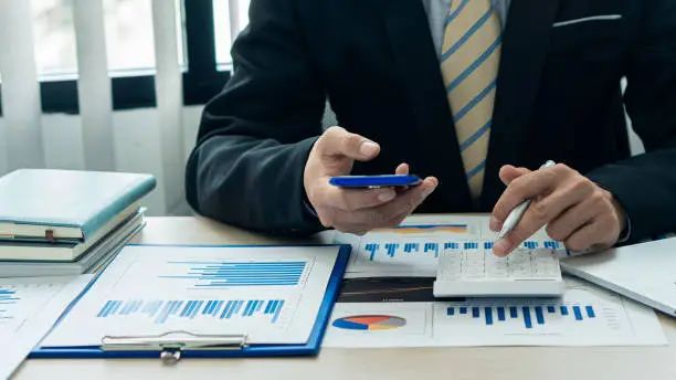 Business men and women holding smartphones at work. Project statistics. Financial data sales chart on the table. close-up view